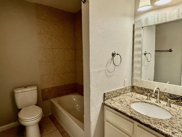 a bathroom with a granite countertop sink a toilet and bathtub