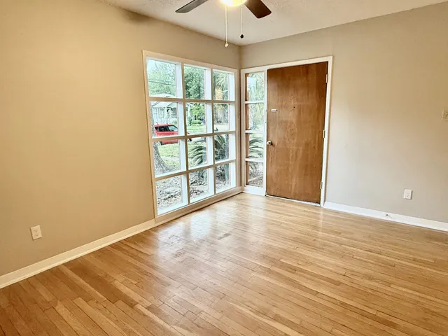 a view of an empty room with a window and wooden floor