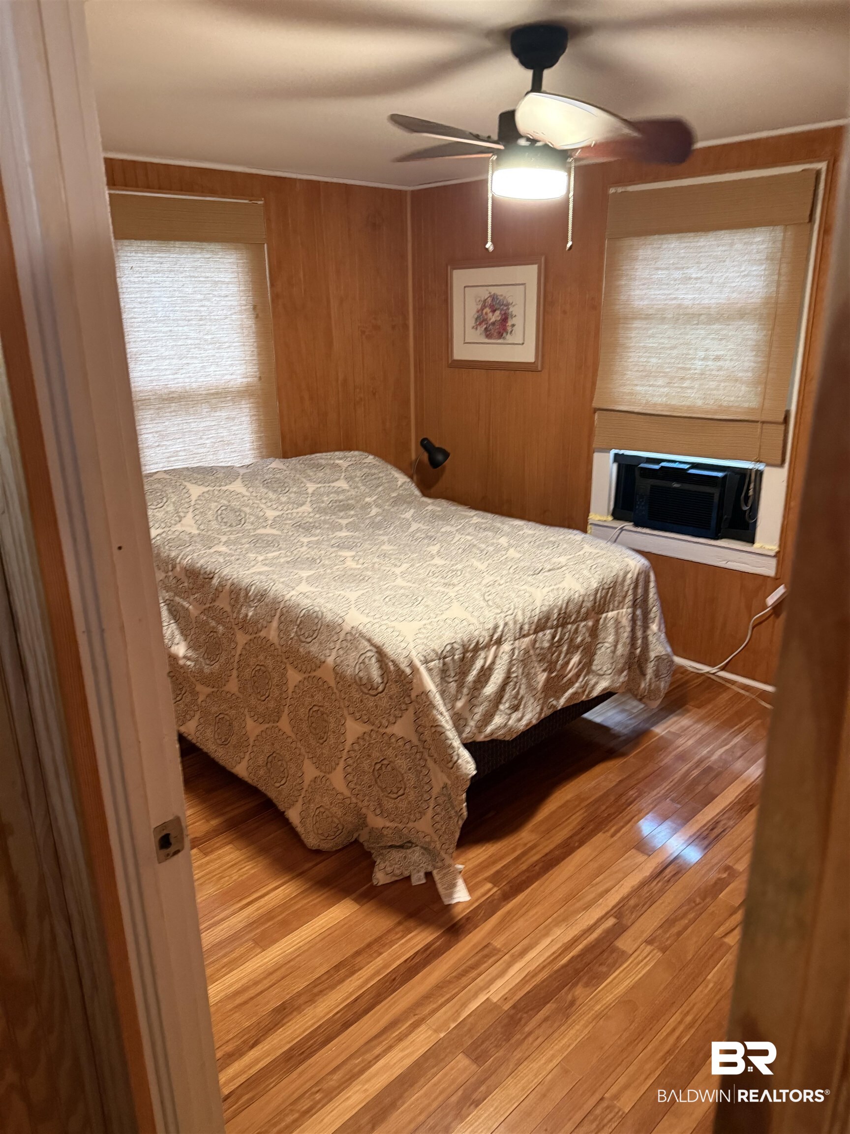 12990 Groves Road Summerdale, AL 36580 - Photo 5 of 8 Bedroom with a fireplace, wooden walls, a ceiling fan, and wood finished floors