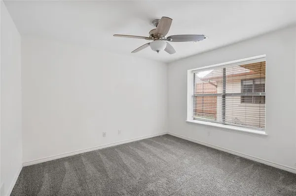 an empty room with a ceiling fan and a window