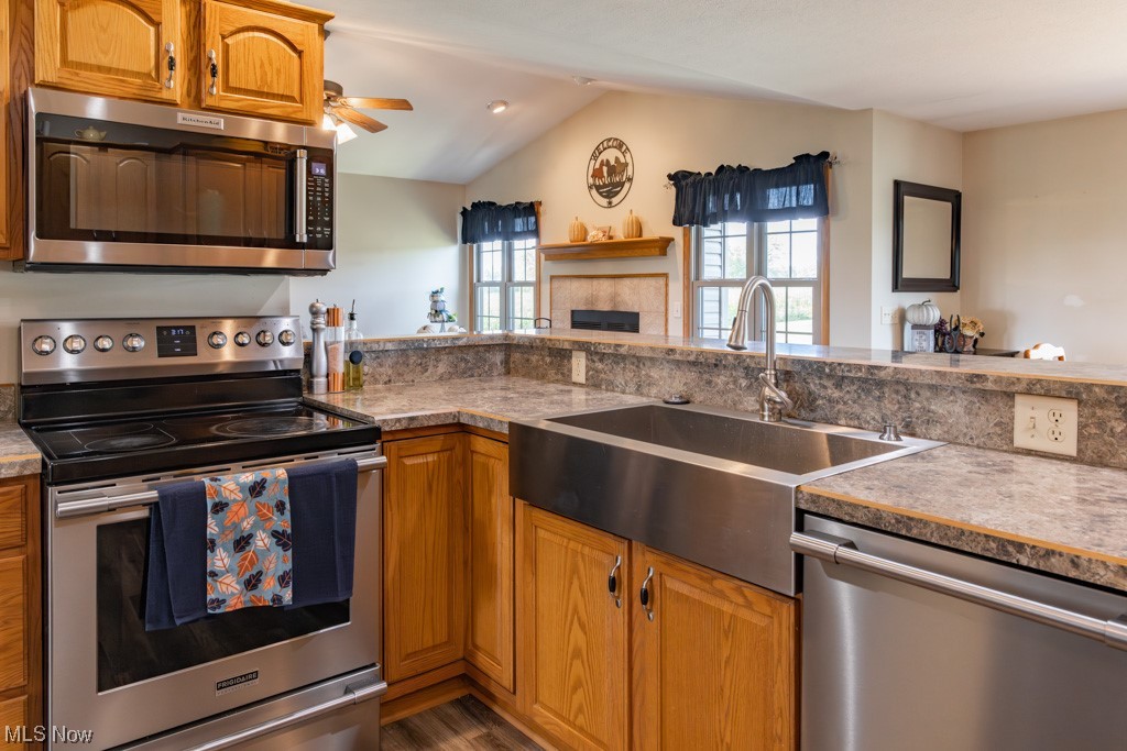 8383 Ickes Road Wooster, OH 44691 - Photo 19 of 32 Kitchen with a tiled fireplace, vaulted ceiling, ceiling fan, appliances with stainless steel finishes, and wood-type flooring