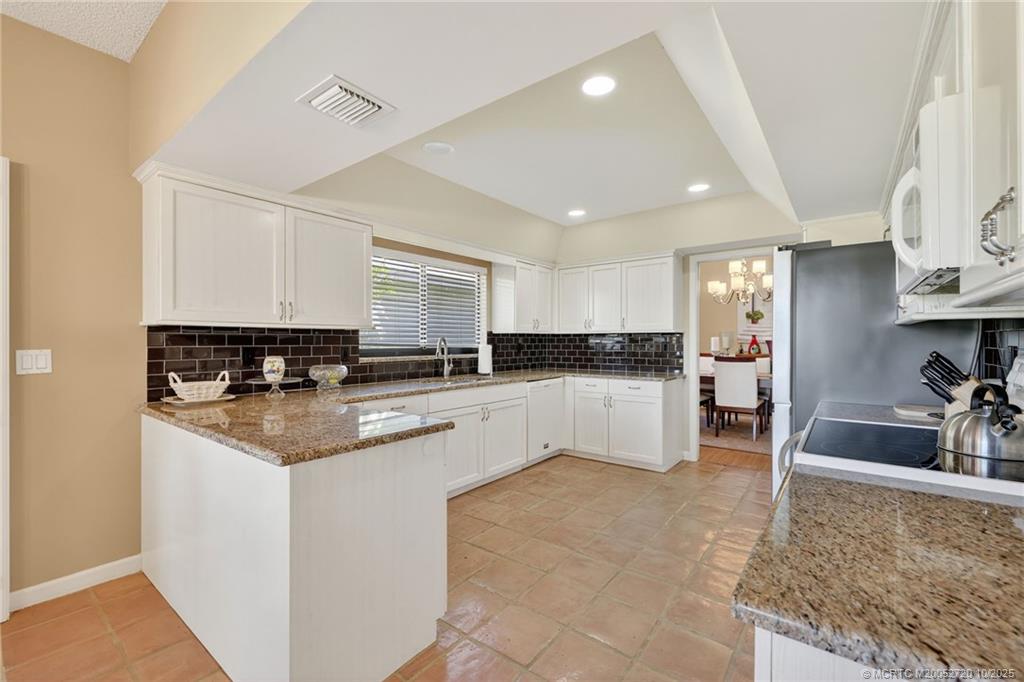 6957 Southeast Pacific Drive Stuart, FL 34997 - Photo 16 of 71 a kitchen with stainless steel appliances granite countertop a sink and cabinets