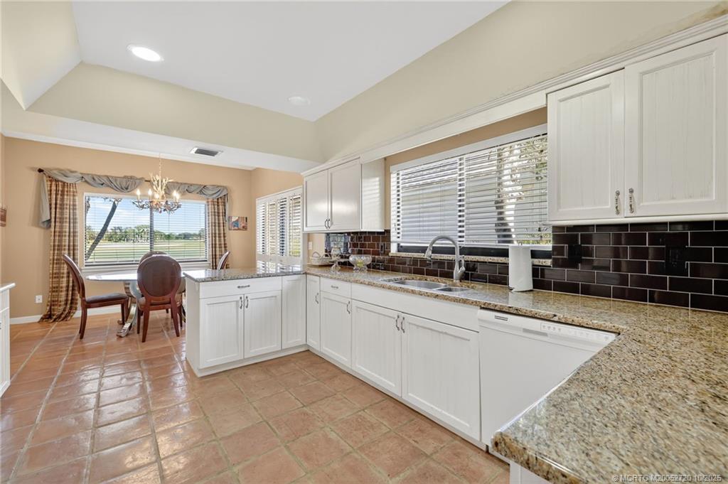 6957 Southeast Pacific Drive Stuart, FL 34997 - Photo 17 of 71 a large white kitchen with granite countertop a stove a sink a dining table and chairs