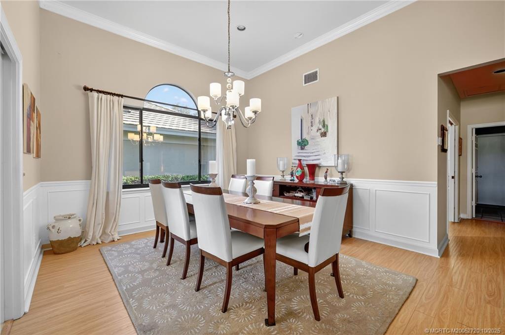 6957 Southeast Pacific Drive Stuart, FL 34997 - Photo 7 of 71 a dining room with furniture wooden floor a rug a potted plant and a chandelier