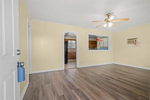 a view of an empty room with wooden floor and a ceiling fan