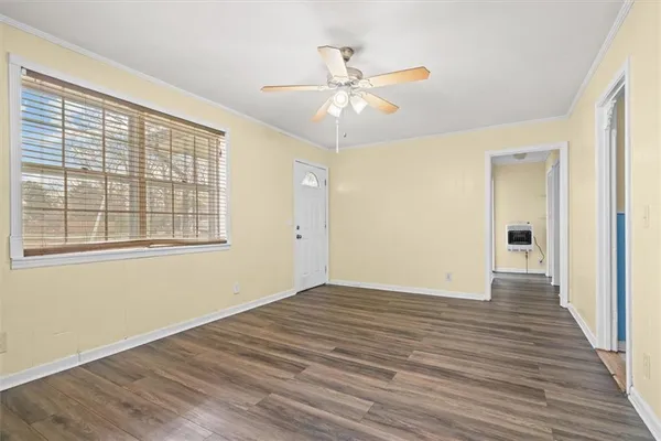 a view of an empty room with wooden floor and a window