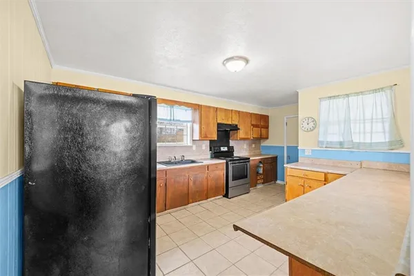 a large kitchen with a refrigerator a stove top oven a sink dishwasher and wooden cabinets with wooden floor