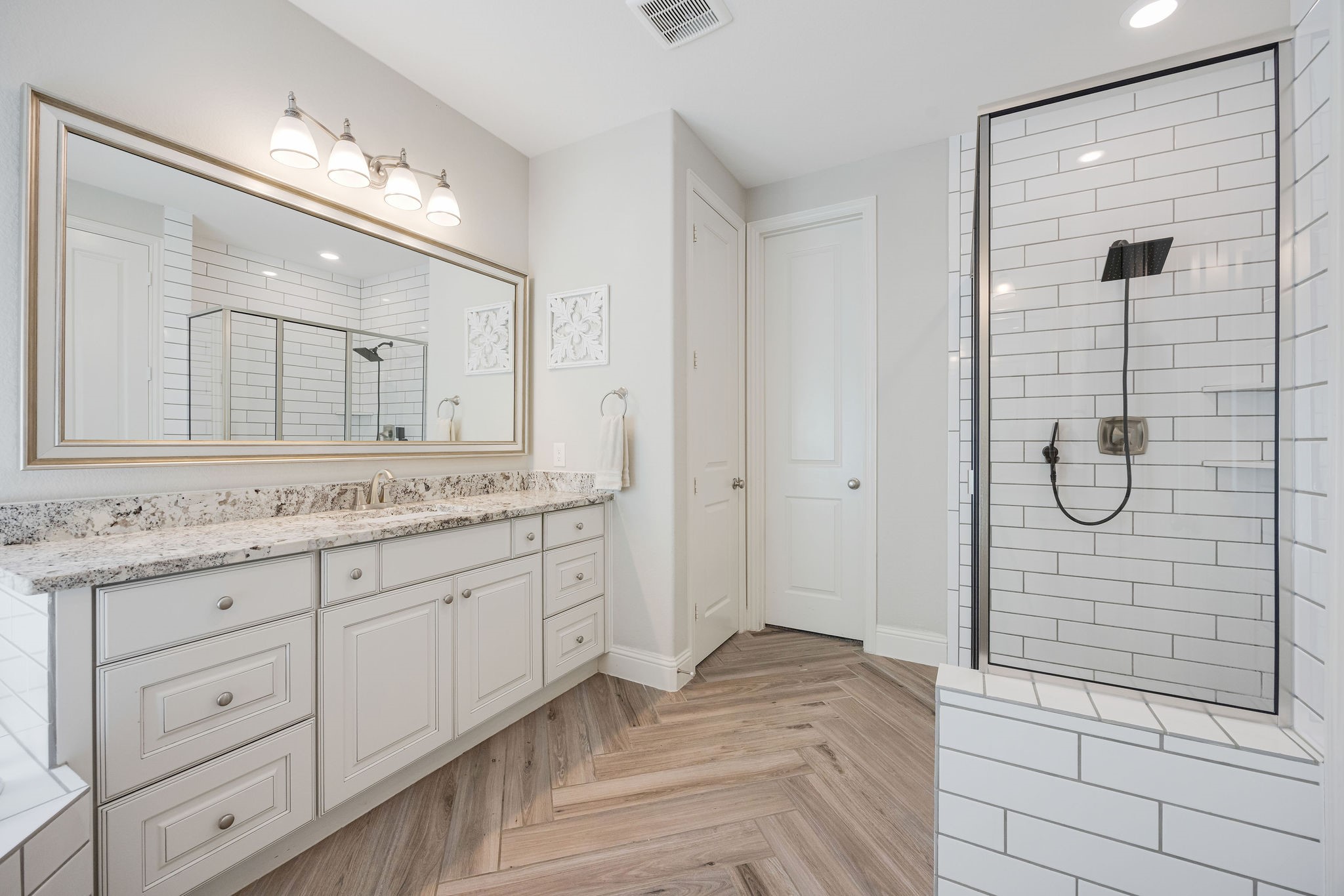 13103 Six Rivers Drive Humble, TX 77346 - Photo 14 of 44 The en-suite bath features dual sinks, granite counters, a soaking tub, and a walk-in shower complemented by statement mirrors, and stunning herringbone tile detail.