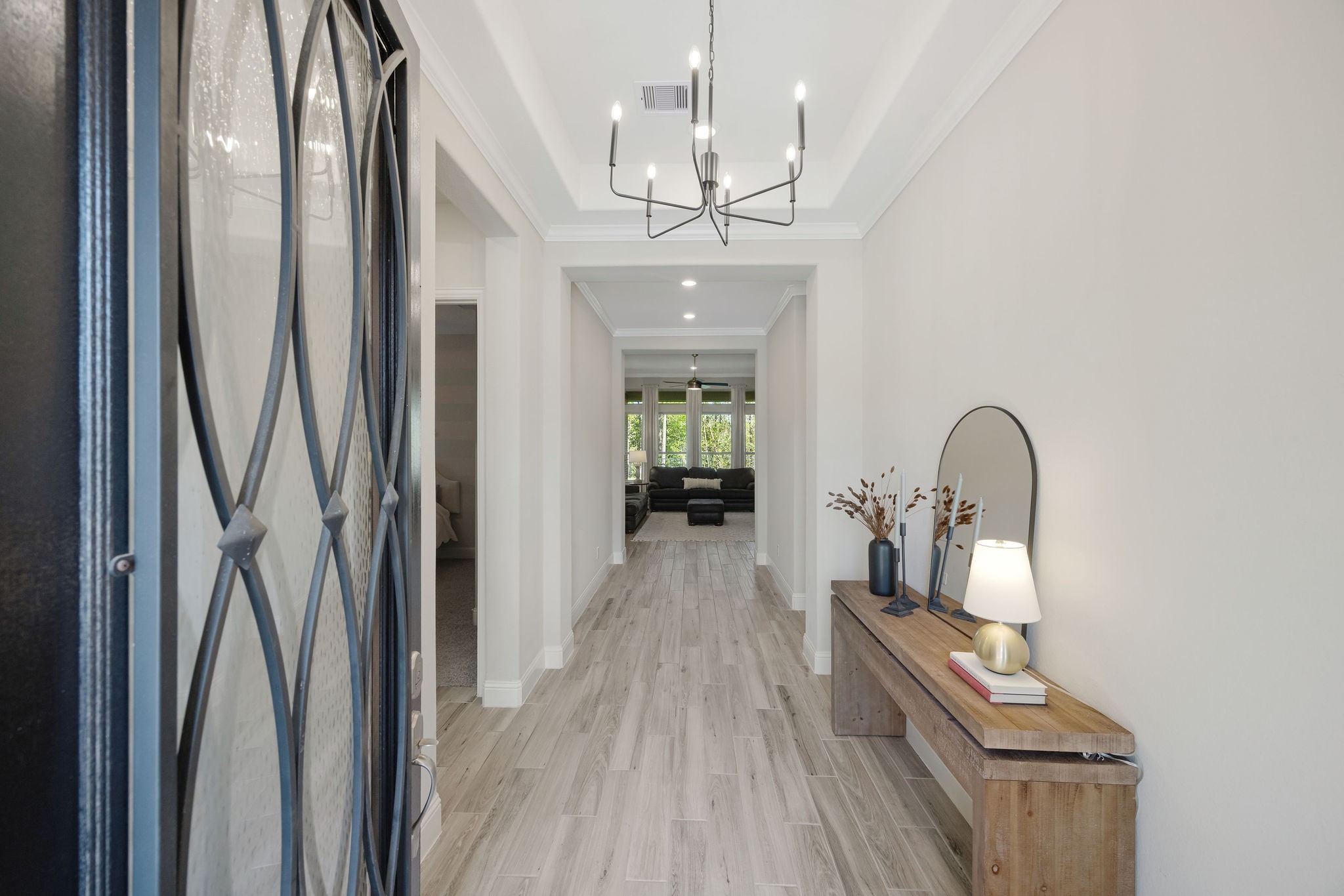 13103 Six Rivers Drive Humble, TX 77346 - Photo 41 of 44 A welcoming foyer makes a strong first impression, featuring wood-look tile, high ceilings, and a statement wood door, accented by tray ceilings, crown moulding, and a decorative light fixture.