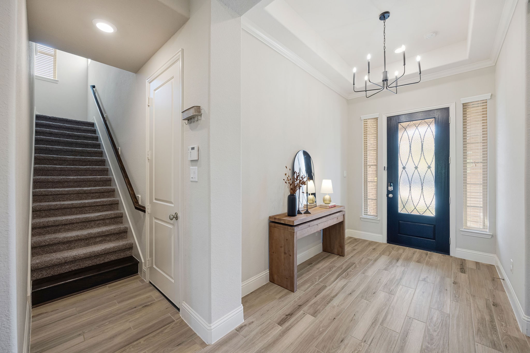 13103 Six Rivers Drive Humble, TX 77346 - Photo 42 of 44 A welcoming foyer makes a strong first impression, featuring wood-look tile, high ceilings, and a statement wood door, accented by tray ceilings, crown moulding, and a decorative light fixture.