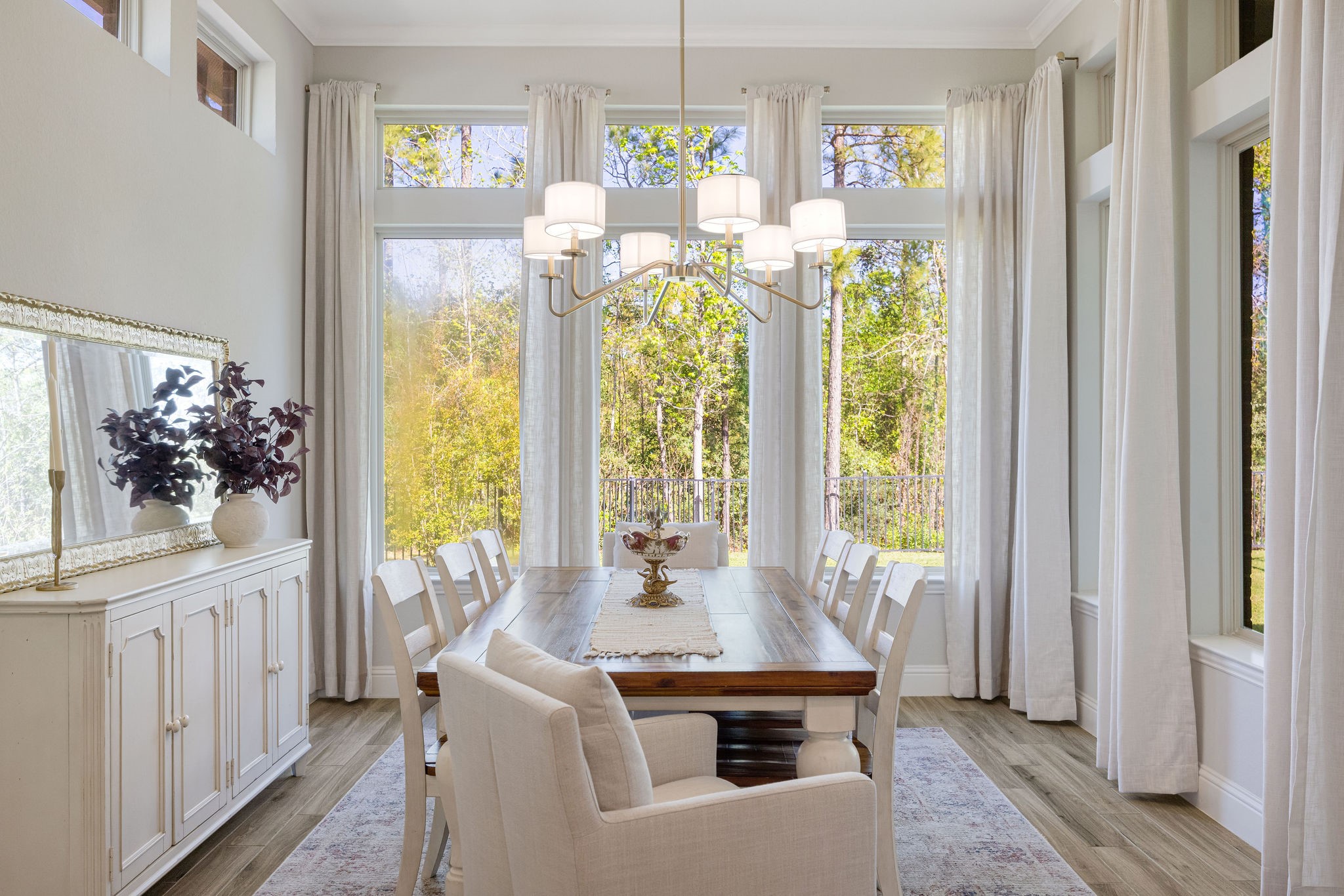 13103 Six Rivers Drive Humble, TX 77346 - Photo 9 of 44 Featuring a statement gold light fixture, elevated ceilings, and a wall of windows, with a door leading to the covered backyard patio for seamless indoor-outdoor flow.