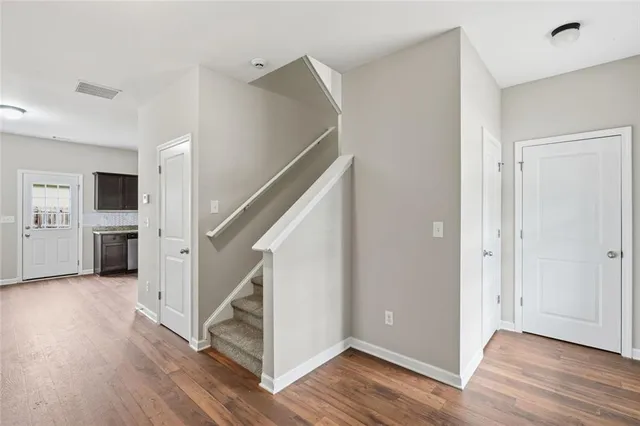 a view of front door with hallway and wooden floor