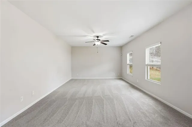 an empty room with windows and fan