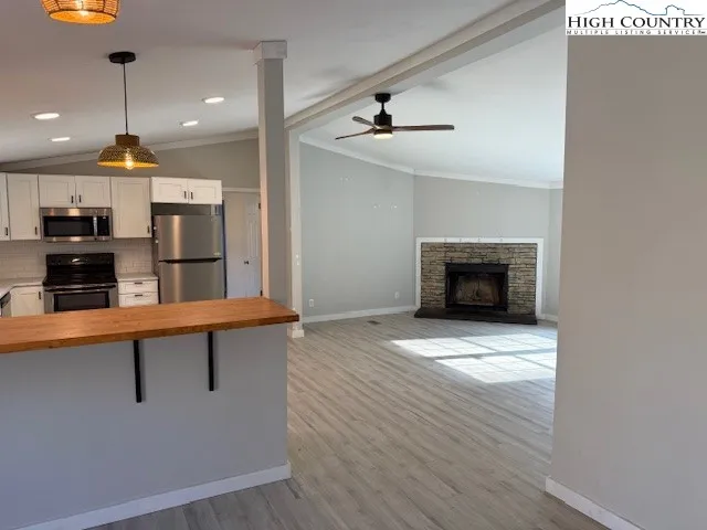 an empty room with wooden floor fire place and windows
