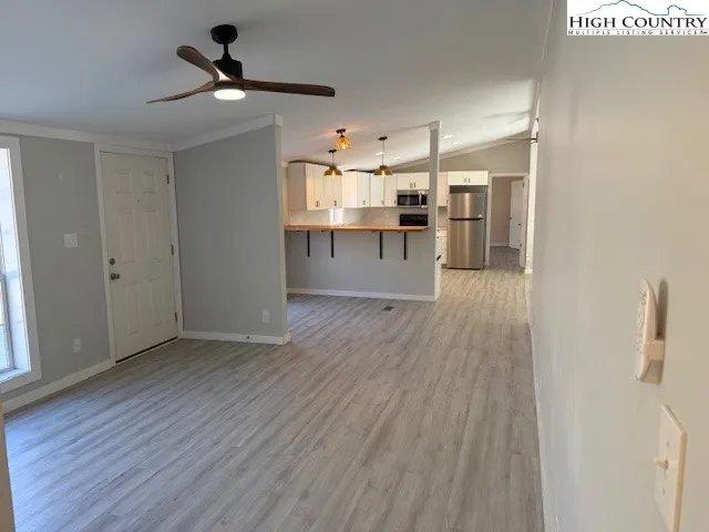 a view of a kitchen with wooden floor a ceiling fan and windows