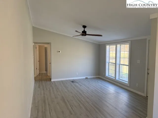 a view of an empty room with window and wooden floor