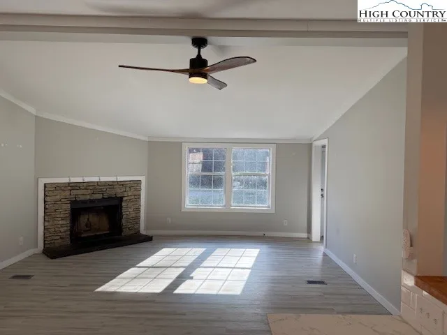 a view of an empty room with exposed radiator and a fireplace