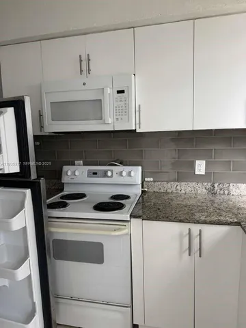 a kitchen with granite countertop white cabinets and white appliances