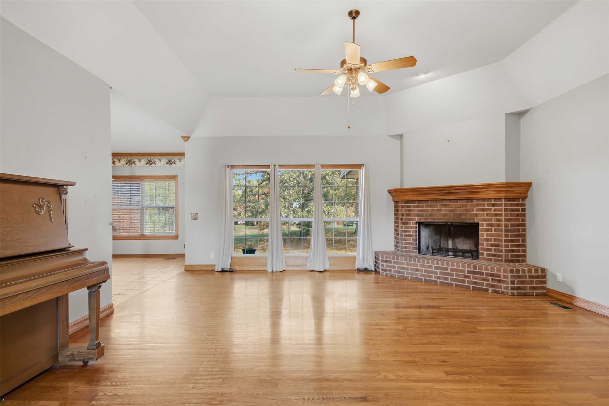 17875 East 589 Road Inola, OK 74036 - Photo 4 of 73 Vaulted ceilings, wood-finish flooring, brick fireplace with wood mantel, large windows, and a ceiling fan