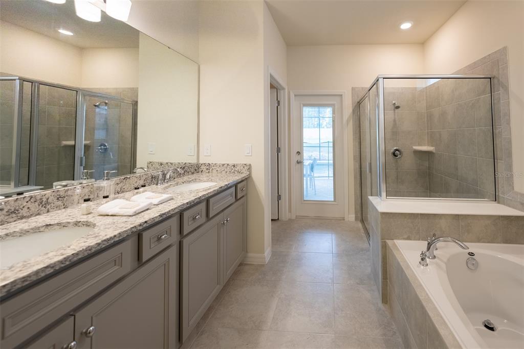 4470 Kaipo Road Davenport, FL 33897 - Photo 12 of 34 a bathroom with a sink double vanity granite tub shower and a mirror