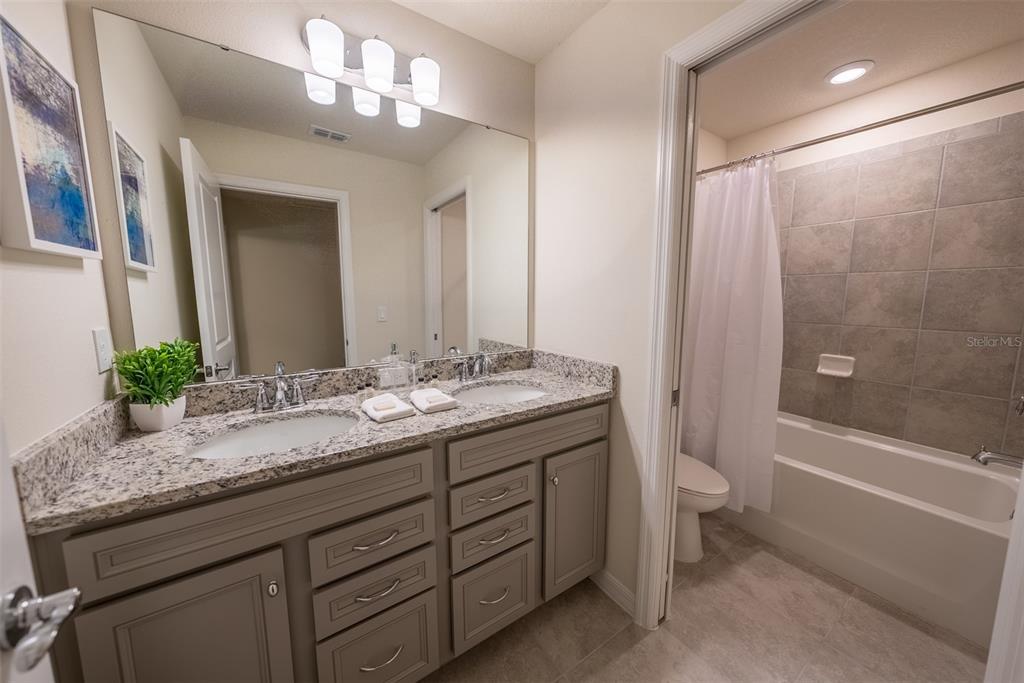 4470 Kaipo Road Davenport, FL 33897 - Photo 21 of 34 a bathroom with a granite countertop sink toilet and shower