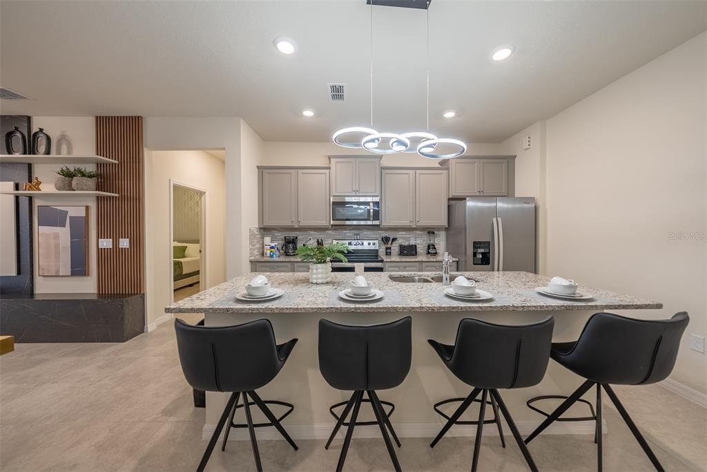 4470 Kaipo Road Davenport, FL 33897 - Photo 3 of 34 a kitchen with stainless steel appliances kitchen island granite countertop a dining table and chairs