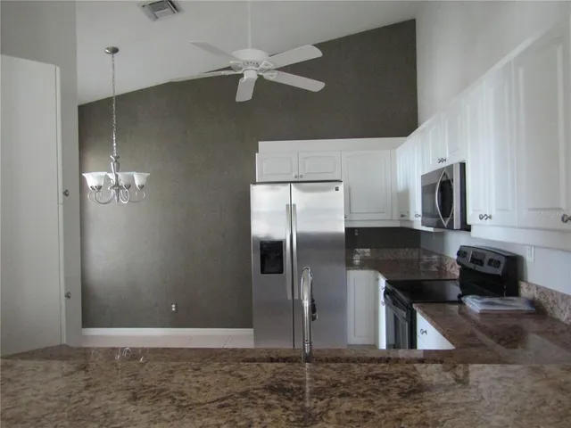 a kitchen with stainless steel appliances kitchen island granite countertop a refrigerator a stove and a sink with wooden floor