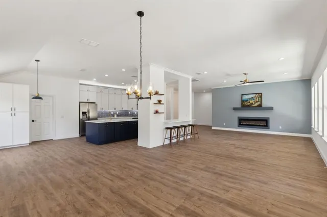 a view of a kitchen with kitchen island a sink wooden floor and a large window