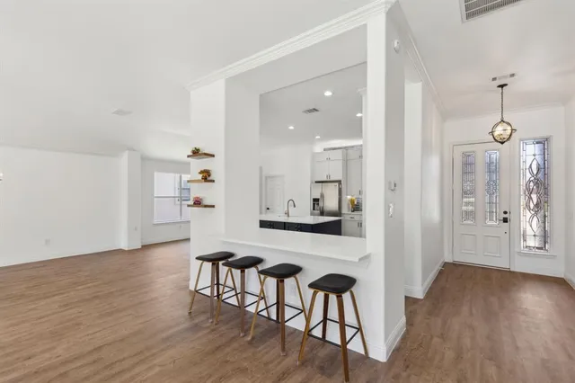 a view of a hallway with wooden floor and a kitchen