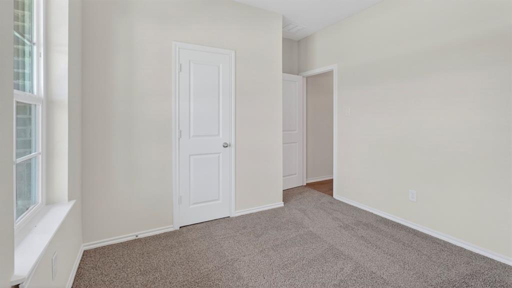 1683 Mantle Road Crandall, TX 75114 - Photo 24 of 31 Neutral-toned room with light gray walls, plush gray carpet, a two-panel interior door with brushed nickel hardware, and a white-framed window