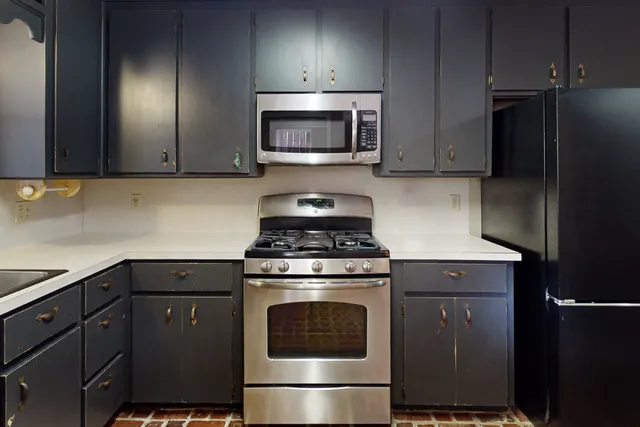 a kitchen with granite countertop a stove top oven and cabinets
