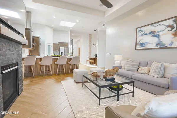 a living room with couches a coffee table and kitchen view with wooden floor