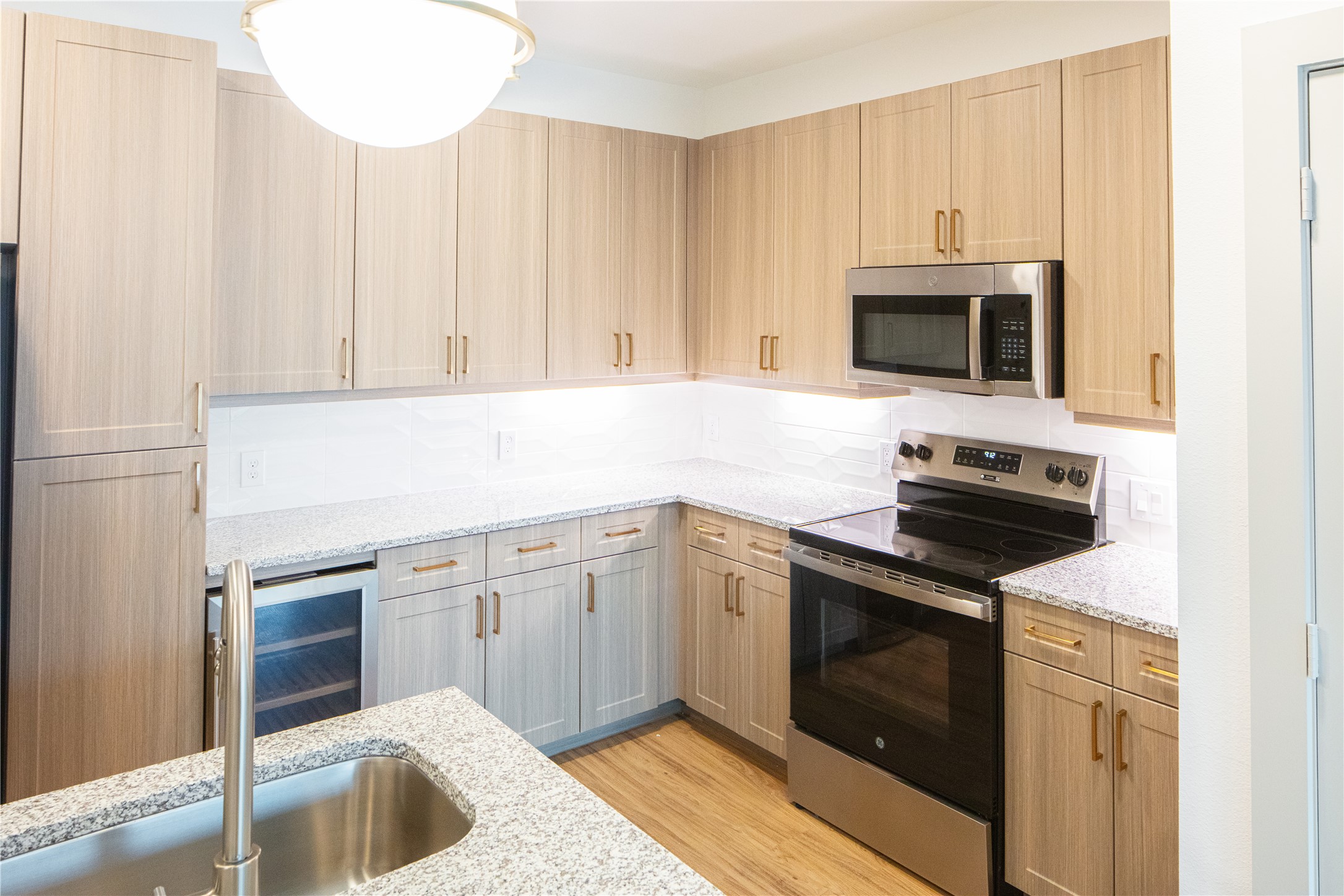 3100 Scofield Ridge Parkway, Unit 1403 Austin, TX 78727 - Photo 10 of 21 a kitchen with granite countertop a sink dishwasher stove and microwave with wooden floor