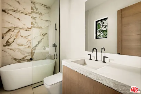 a bathroom with a granite countertop bathtub sink vanity mirror and toilet