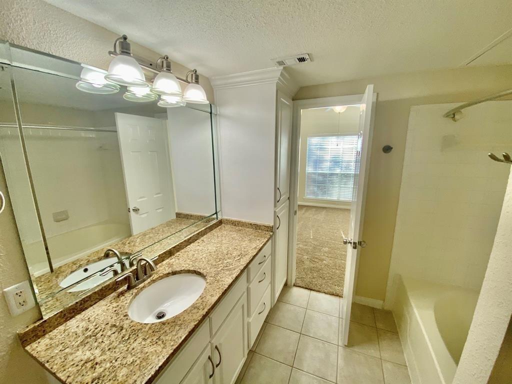 a bathroom with a granite countertop sink a mirror and a shower