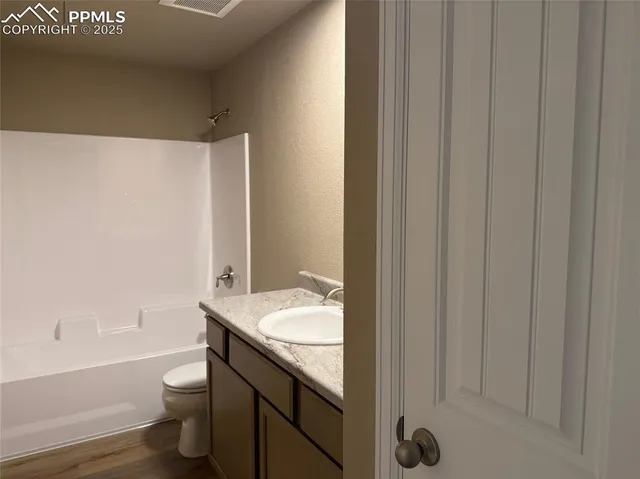 a bathroom with a granite countertop bathtub shower sink vanity and toilet