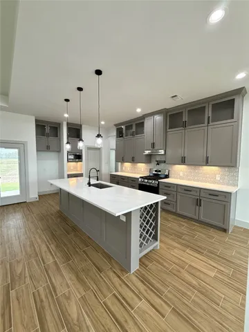 a kitchen with stainless steel appliances kitchen island granite countertop a sink and a stove