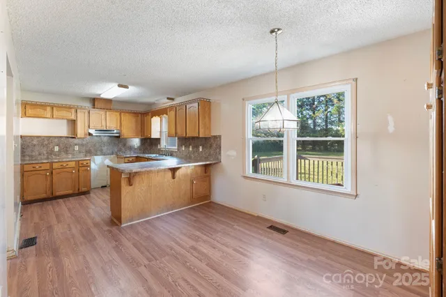 a kitchen with kitchen island granite countertop wooden floors and white cabinets