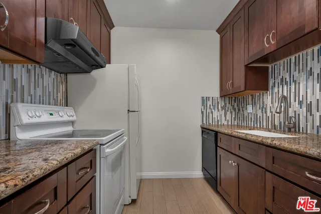 a kitchen with granite countertop a sink a stove and a wooden floors