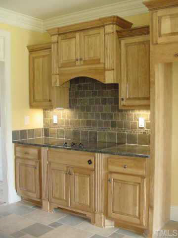 Another kitchen view that showcases the tiled back splash, smooth top built in range with down draft. Other