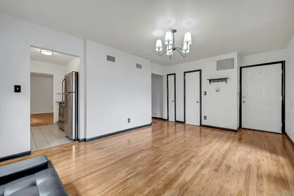 a view of an empty room with wooden floor and a kitchen