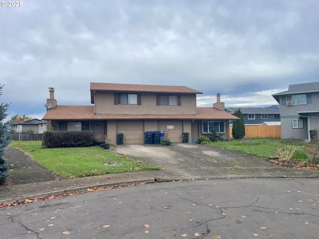 a view of a house with a yard and large tree