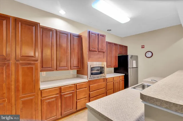 a large kitchen with kitchen island granite countertop wooden cabinets and stainless steel appliances