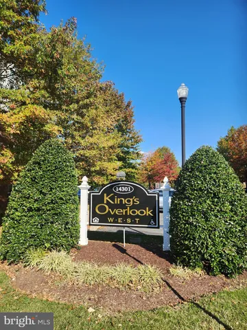 a sign board with a house in the background