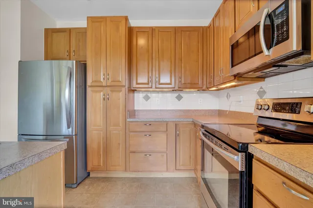 a kitchen with stainless steel appliances granite countertop a refrigerator and a stove