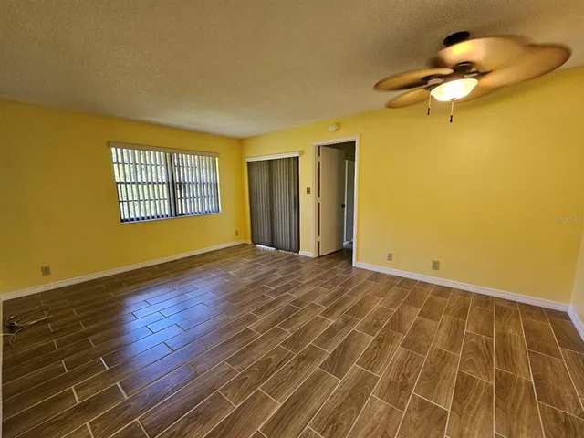a view of an empty room with window and wooden floor
