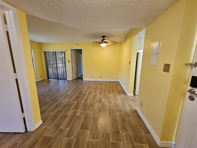 a view of an empty room with a window and wooden floor