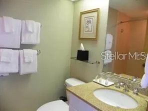 a bathroom with a granite countertop toilet sink and mirror