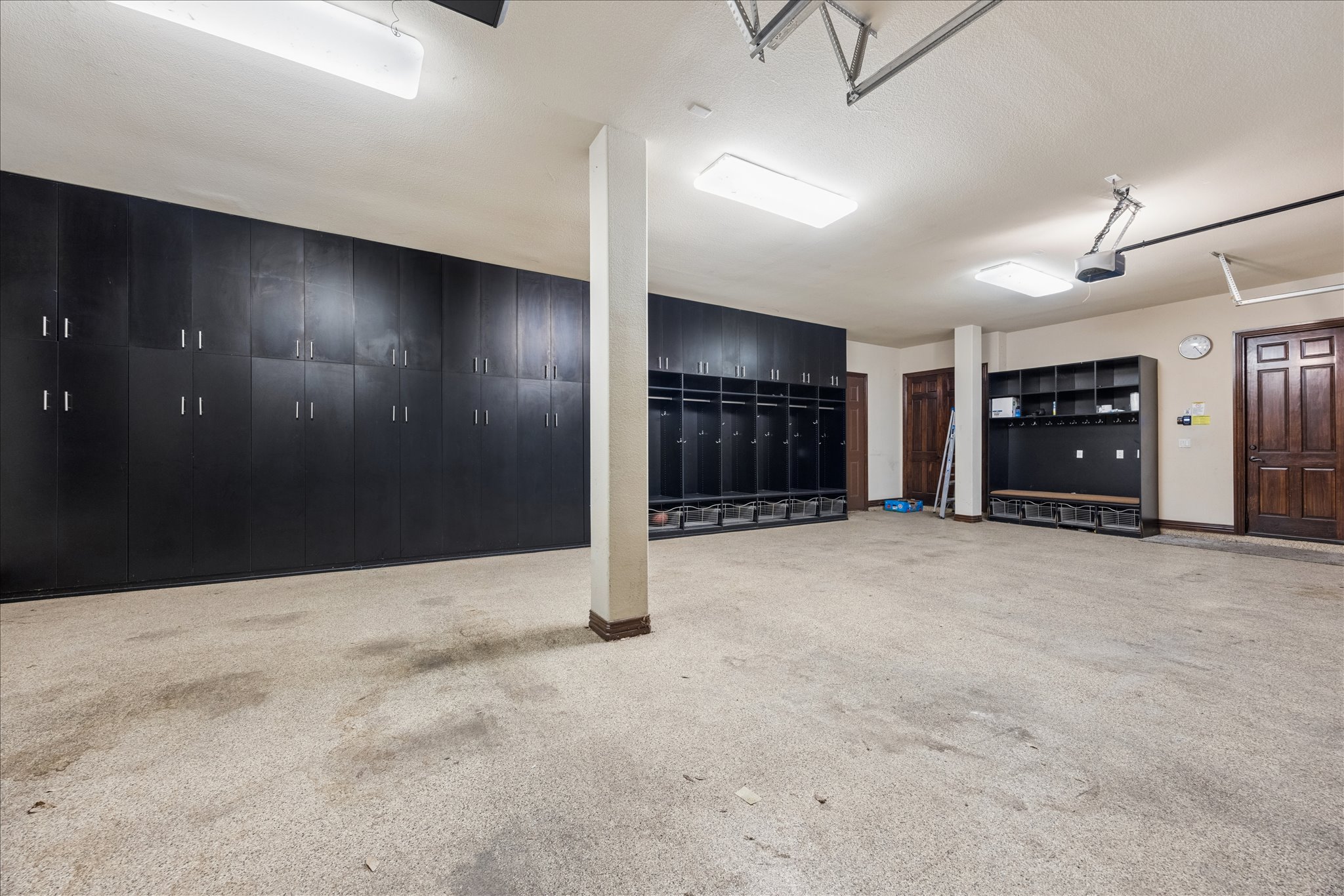 11805 Ranchview Court Austin, TX 78732 - Photo 28 of 36 Spacious garage featuring extensive built-in dark cabinetry and shelving, exposed ceiling joists, and a light-colored speckled concrete floor