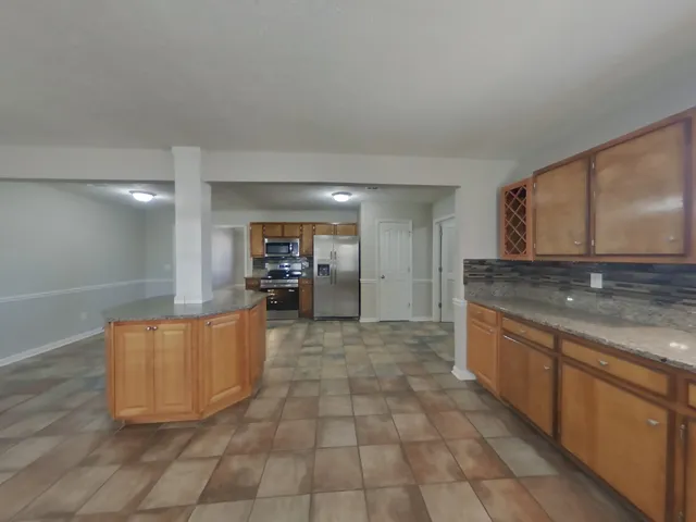 a large kitchen with stainless steel appliances granite countertop a stove a sink and a refrigerator